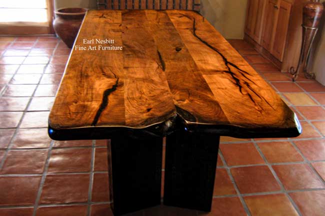 modern mesquite dining table from other end showing ebonized live edge, split in alder legs on base and solid mesquite top